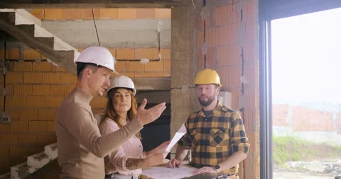 Construction worker showing the progress of a house build to an adult coupl.. Video stock 336251305
