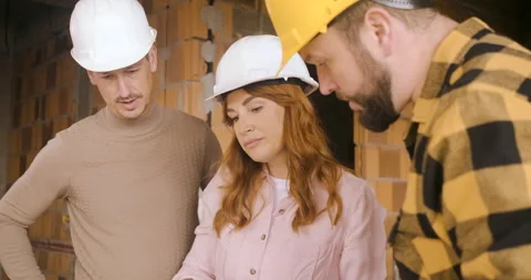 Construction worker showing the progress of a house build to an adult coupl.. Video stock 336251372