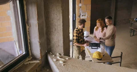 Construction worker showing the progress of a house build to an adult coupl.. Video stock 336251383