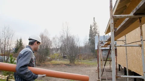 Construction worker on site carry pipe. Builder playfully carries a water pipe Stock Footage 96988084