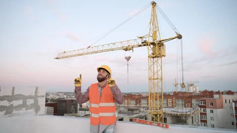 Construction worker on site with crane thumbs up during sunset in the city Stock Footage 295960600