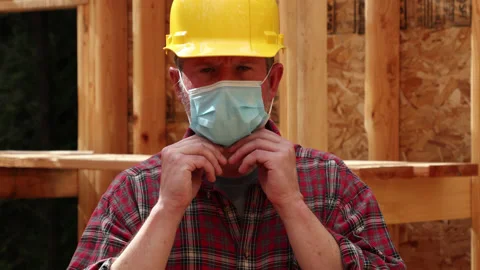 Construction worker on site puts on a medical face mask; COVID-19 theme Stock Footage 139946907