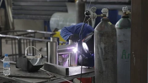 Construction worker at the site welding metal pipes with special blue helmet Stockbeeldmateriaal 142876207