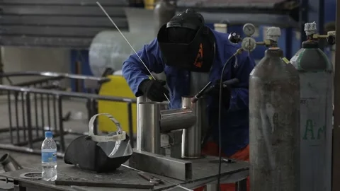 Construction worker at the site welding metal pipes with special blue helmet Vídeo Stock 142884248