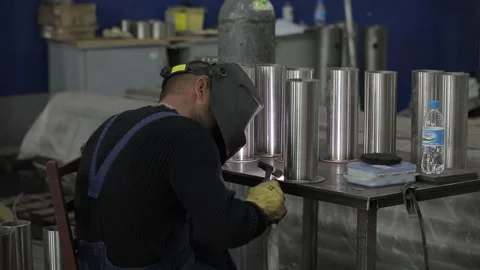 Construction worker at the site welding metal pipes with special blue helmet Stock Footage 142886226