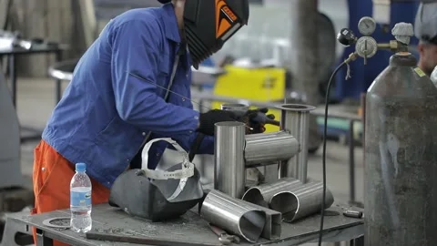 Construction worker at the site welding metal pipes with special blue helmet Stock Footage 142887484