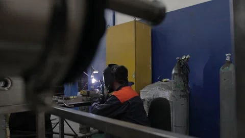 Construction worker at the site welding metal pipes with special blue helmet Stock Footage 142889416