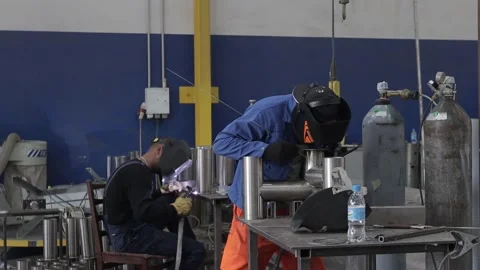 Construction worker at the site welding metal pipes with special blue helmet Stock Footage 142890727