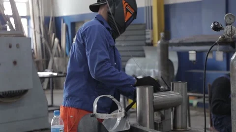 Construction worker at the site welding metal pipes with special blue helmet Video stock 142898828