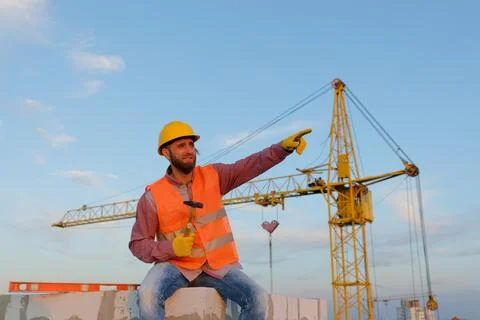 Construction worker sitting and holding hammer at construction site Stock Photos