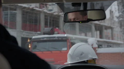 Construction worker sitting in car grips hard hat at jobsite Stock Footage 324912888