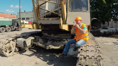 Construction worker sitting on large crawler cranes and eats a burger. Video stock 52250953