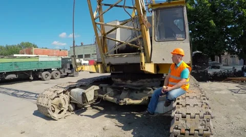 Construction worker sitting on large crawler cranes and eats a burger. 库存影片 52251106
