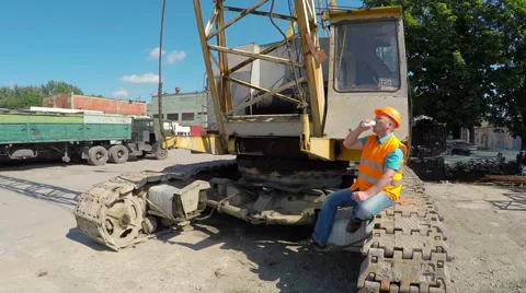 Construction worker sitting on large crawler cranes and drinks. Stock Footage 52251155