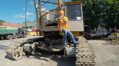 Construction worker sitting on large crawler cranes and eating an apple. Video stock 52251209