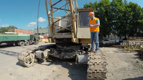 Construction worker sitting on large crawler cranes and eating an apple. Stockbeeldmateriaal 52251316