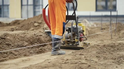 A Construction Worker Skillfully Operating a Vibratory Plate Compactor at a Stock Footage 312635580