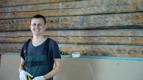 A construction worker is smiling cheerfully at the camera. In his hands he holds Stock Footage 101384407