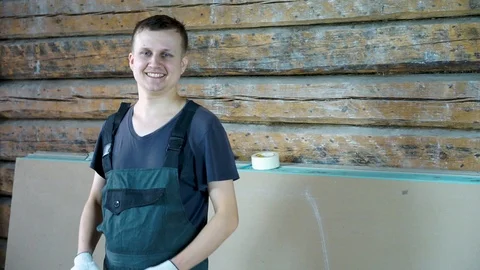 A construction worker is smiling cheerfully at the camera. In his hands he holds Stock Footage 101384420