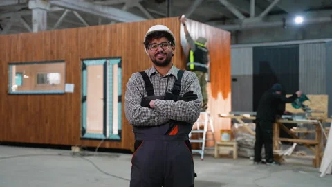 Construction worker smiling with crossed arms in prefabricated house factory Stock Footage 313089533