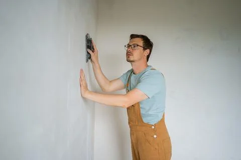 Construction worker smoothing concrete wall with professional plastering Stock Photos