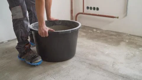 Construction worker in spiked shoes standing by a bucket on a fresh concret.. Stock Photos