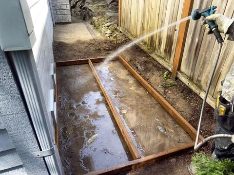 Construction worker spraying water into future concrete pad to prepare for .. Stock Photos