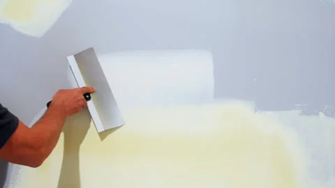 Construction worker spreading joint compound on the drywall wall using a metal Stock Footage 320143096