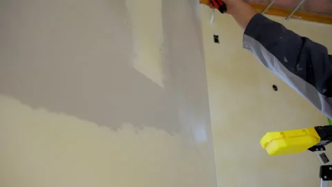 Construction worker spreading joint compound on wall using a metal taping knife Stock Footage 320263282