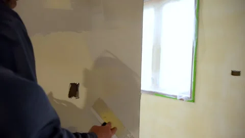 Construction worker spreading joint compound on drywall wall corner using a Stock Footage 320263304
