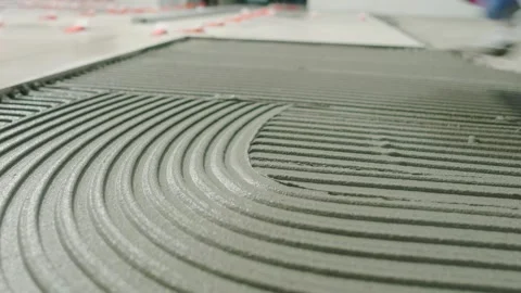 Construction worker spreading tile adhesive on the floor with a notched trowel. Stock Footage 344059217