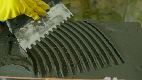 Construction worker spreads cement evenly over tile Stock Footage 283684273