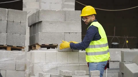 Construction worker stacking concrete blocks at building site Stock Footage 343451348