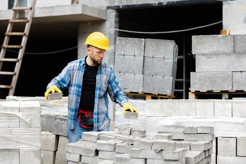 Construction worker stacking concrete blocks at building site Stock Photos