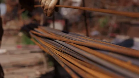 Construction worker stacking steel reinforcement bars at building site 動画素材 347733984