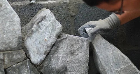 Construction worker stacks stones to build an outdoor fireplace Stock Footage 112292441