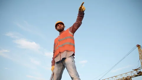Construction worker standing confidently at a construction site under a blue sky Video stock 311308621