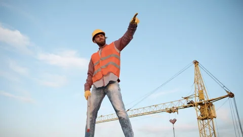 Construction worker standing confidently on site with crane in background Stock Footage 311308852