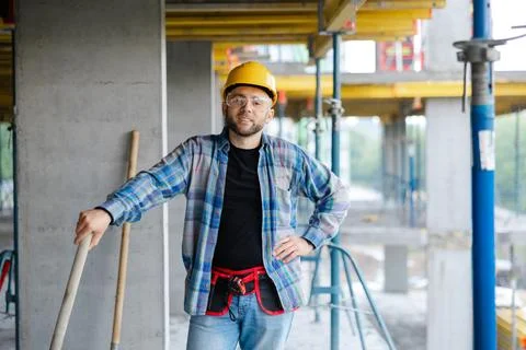 Construction worker standing with shovel at building site Stock Photos