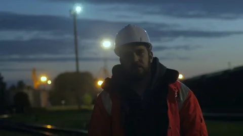 Construction worker standing tired in the twilight. overworking.4k Video stock 83760396