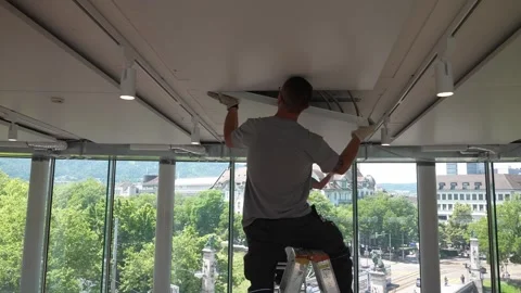 Construction worker stands on ladder attaches ceiling element in bright modern Stock Footage 331305152
