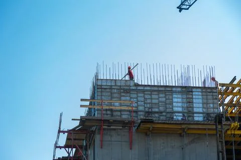 A construction worker stands on the rafters of the upper floor. The builder is Stock Photos