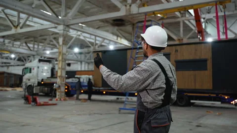 Construction worker supervising prefabricated house loading in factory Stock Footage 313090934