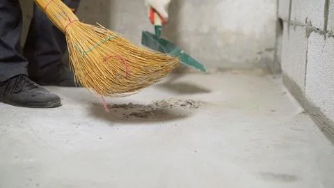 Construction worker sweeping dust with broom and dustpan Stock Photos
