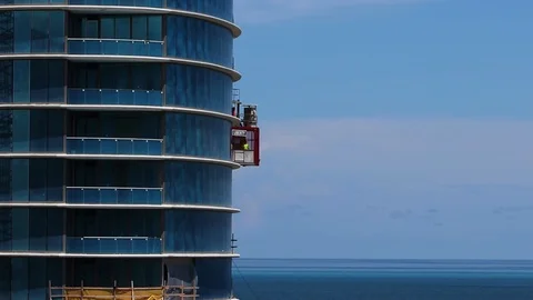 A construction worker takes a construction elevator up a skyscraper. Stock Footage 95947277