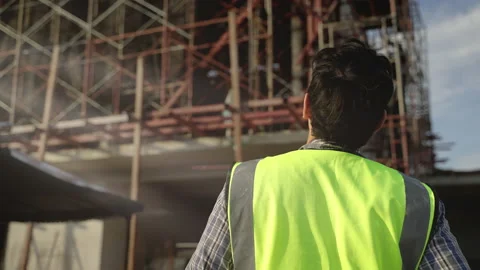Construction worker is taking off his helmet while looking at a construction Stock Footage 226813649