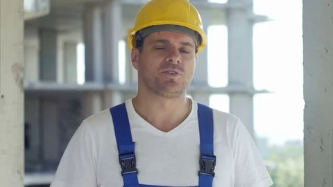 Construction worker talks to camera in front of building site 스톡 동영상 82800658