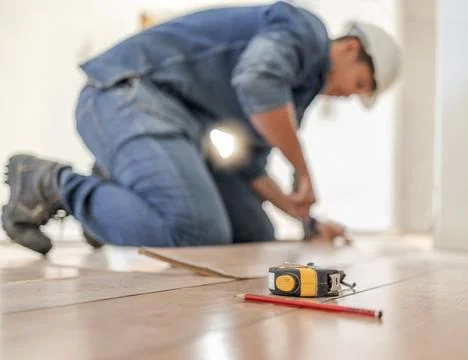 Construction worker tape measure, wood carpenter and home floor renovation of a Stock Photos
