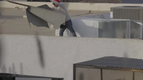 Construction worker throws trash off roof Stock Footage 303641312