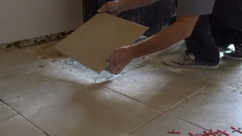 Construction worker is tiling floor at home. Laying tiles on the floor Stock Footage 113827354